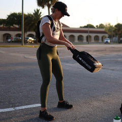Woman rucking outdoors with GORUCK gear, wearing athletic clothing and black cap