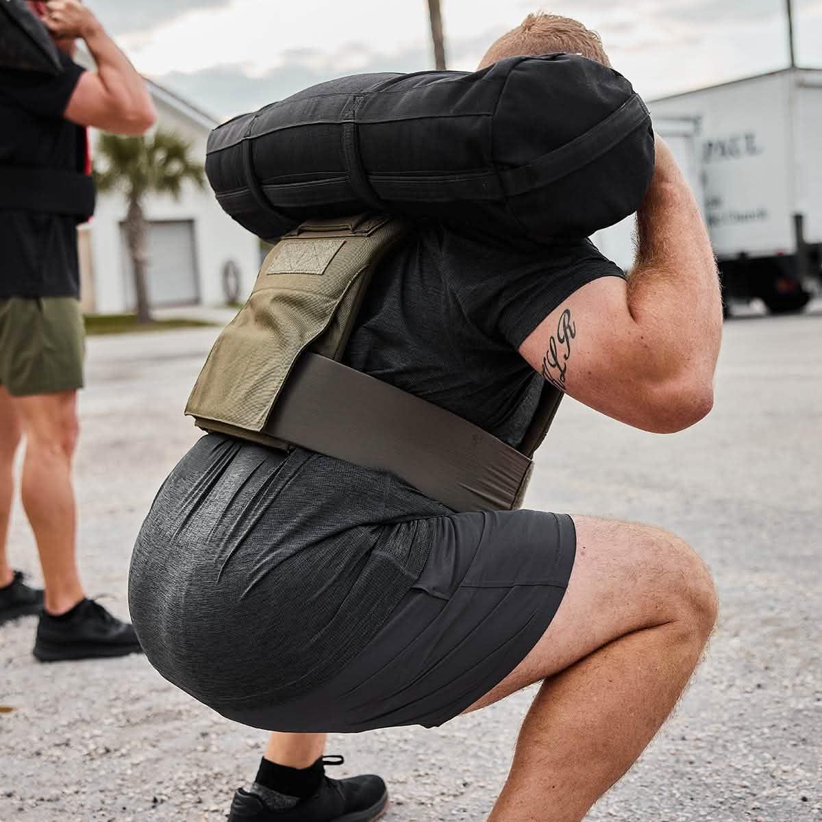 Man performing outdoor squat with GORUCK rucking sandbag and weighted vest