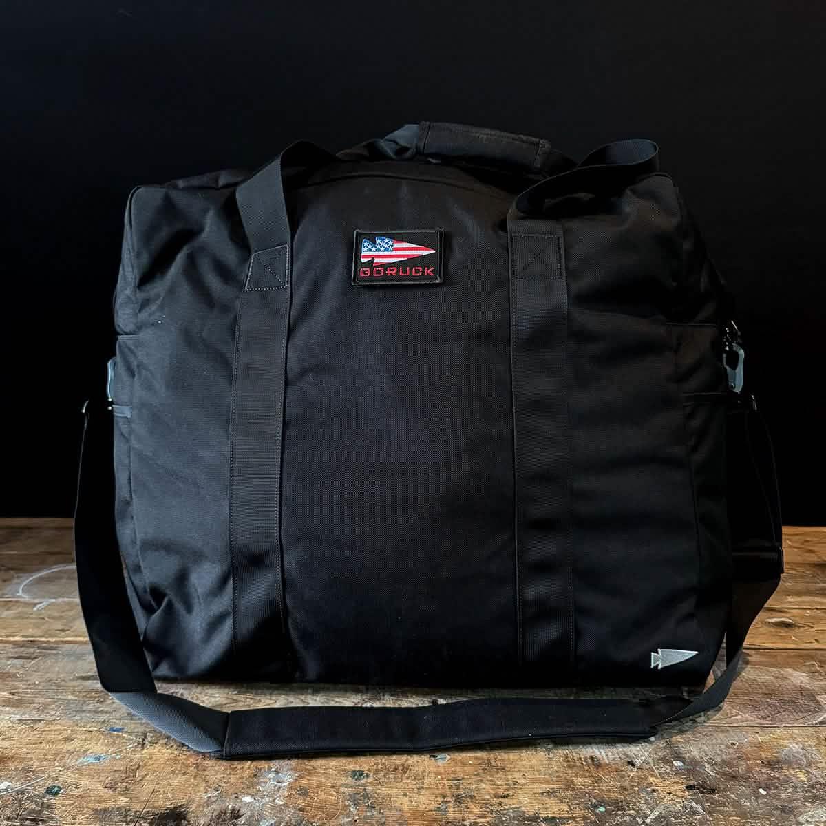 GORUCK black rucksack duffel bag on wooden table, tough rucking gear with logo patch