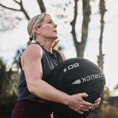 Woman training outdoors with GORUCK 80 lb sandbag, fitness gear for rucking workouts