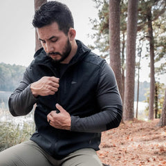 Man wearing GORUCK rucking vest outdoors in pine forest by a lake