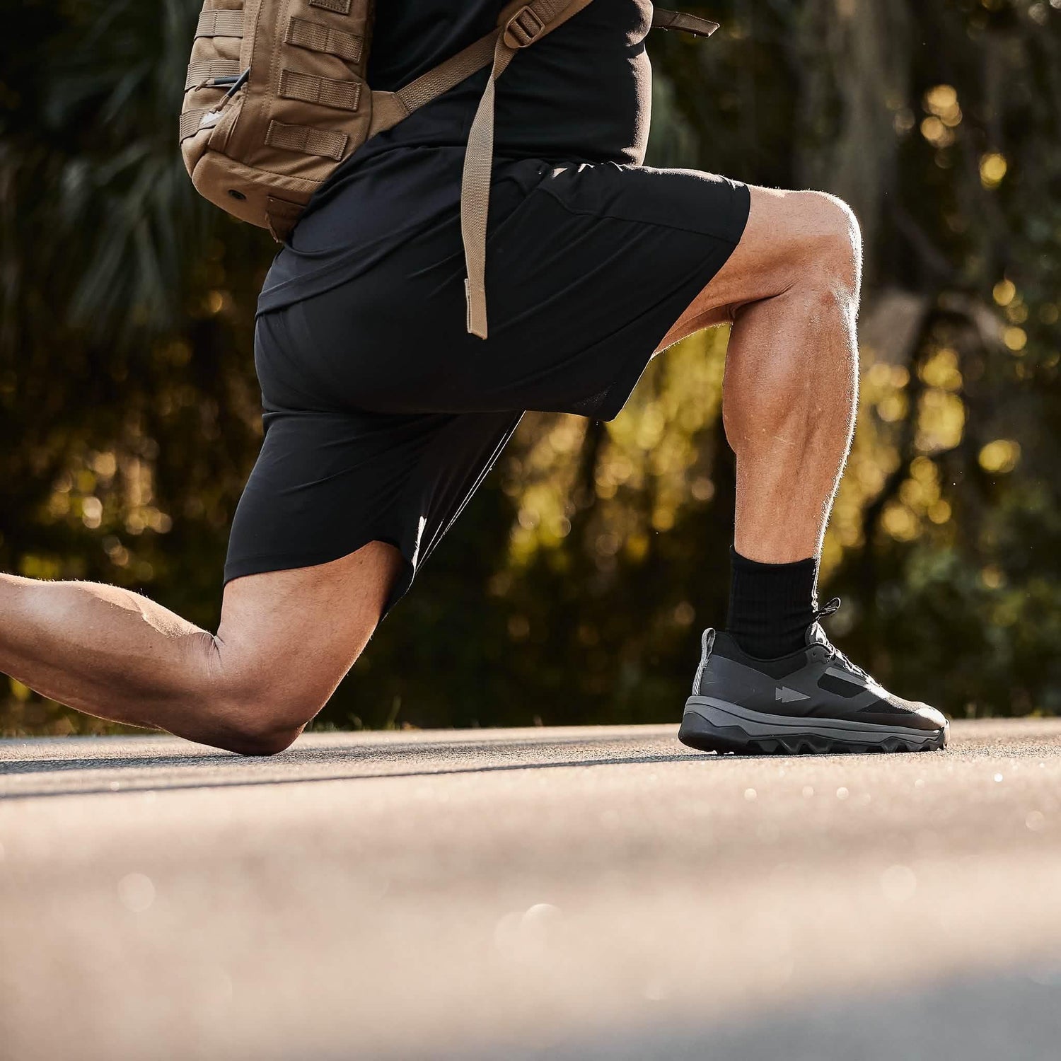 Man performing outdoor lunge in GORUCK gear and backpack, promoting rucking fitness.