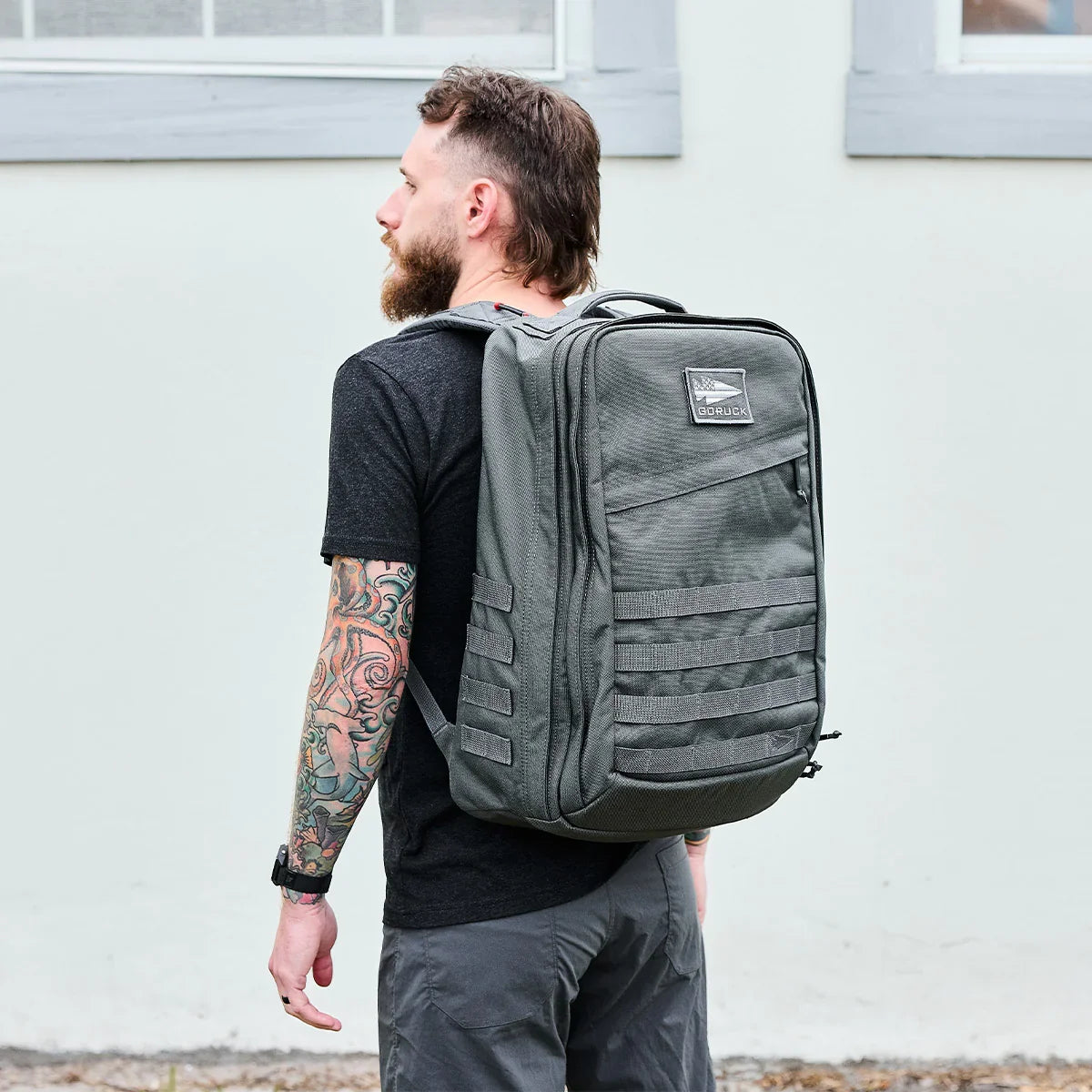 Man wearing a large grey GORUCK rucksack outdoors, showcasing durable rucking gear