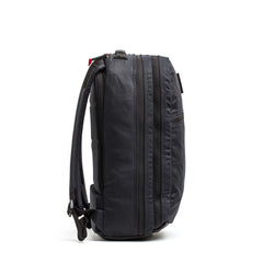 The Double Compartment Bullet Ruck - Heritage Waxed Canvas - 18L stands upright, displayed from the side against a plain white background.
