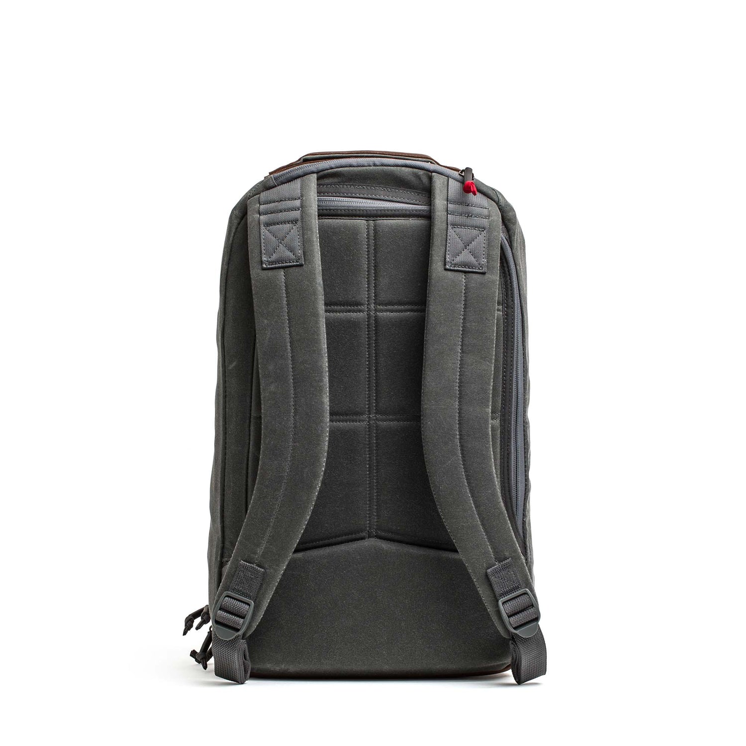 The Double Compartment Bullet Ruck - Heritage Waxed Canvas - 18L is shown from the back, featuring padded shoulder straps and a top handle.