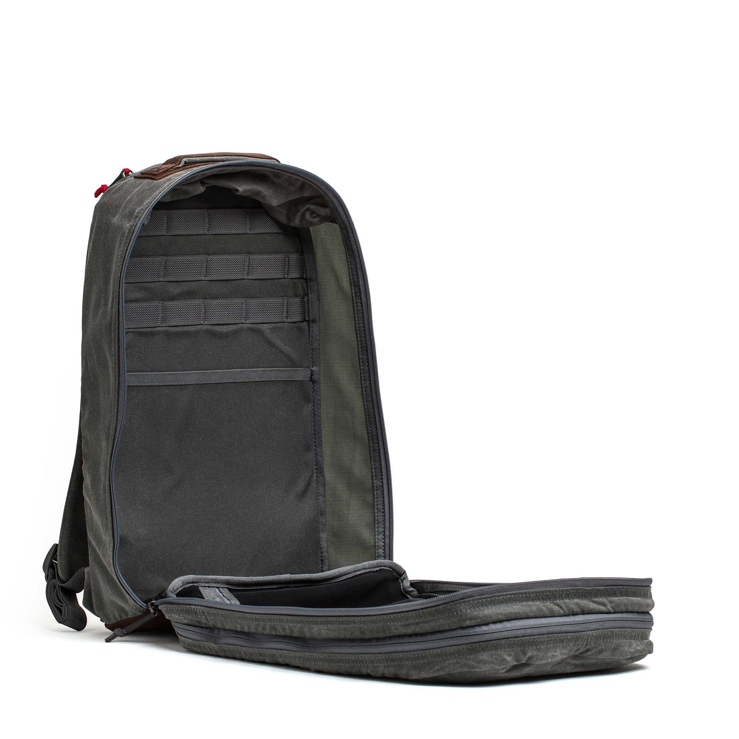 The Double Compartment Bullet Ruck - Heritage Waxed Canvas - 18L, shown fully unzipped, displays its roomy interior and convenient inner pockets—ideal as a rugged travel daypack.