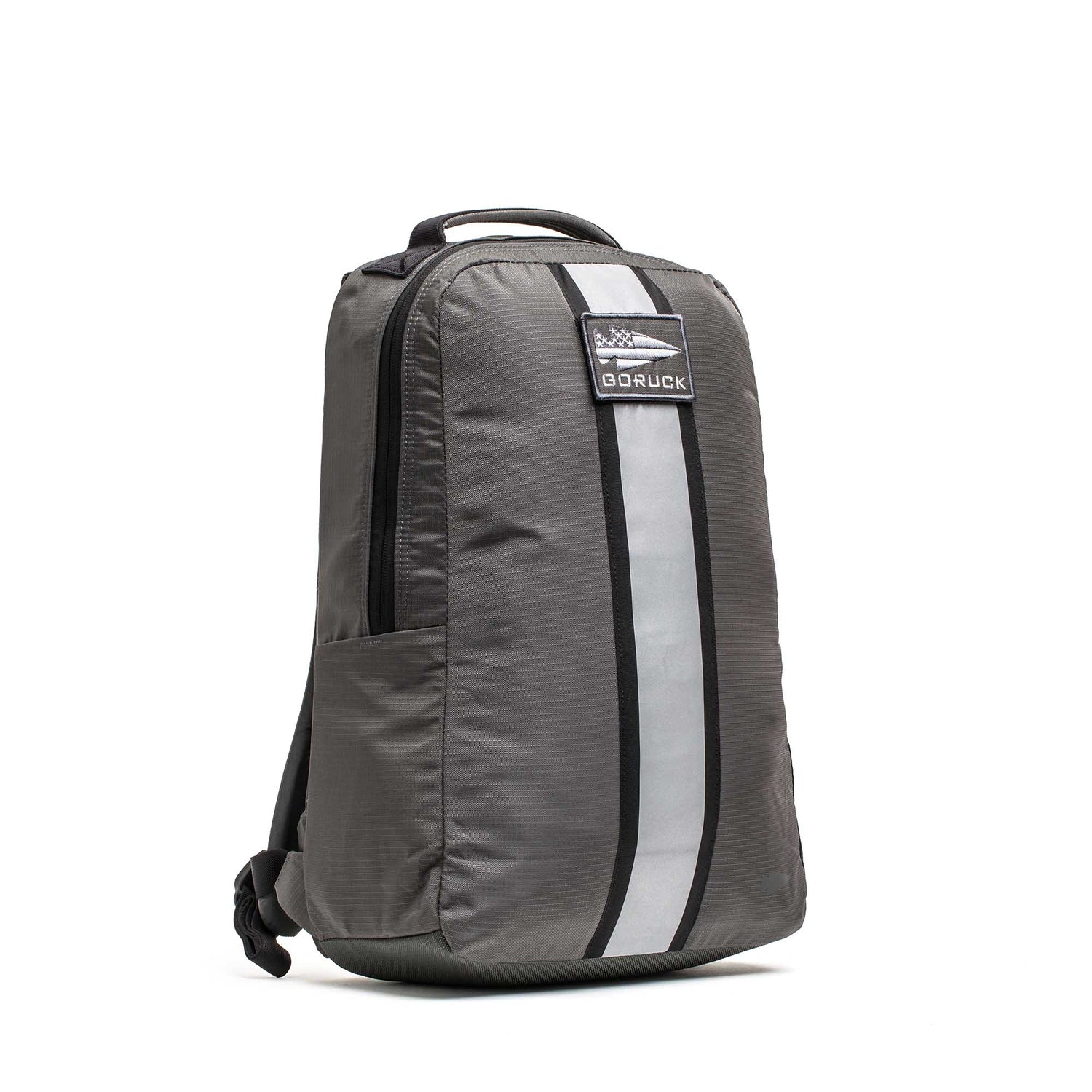 The Basic Rucker is a gray backpack featuring a top handle, front reflective stripe, and GORUCK logo patch—perfect for rucking sessions or carrying your ruck plate. Its durable design ensures comfort for everyday adventures.