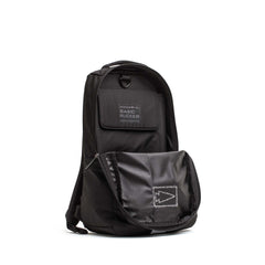 The Basic Rucker backpack, shown in black with its front pocket open to display the label and ruck plate-ready interior, stands upright against a white background—ideal for your next rucking adventure.