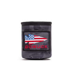 The Ballistic Beer Jacket is a black beer koozie crafted from rugged 1000D CORDURA, featuring an American flag spearhead patch and bold red "GORUCK" text on the front.