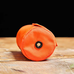 GORUCK orange beer jacket bottle cover on wood table, rugged outdoor gear accessory