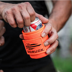 Hand holding a can in an orange GORUCK beer jacket, outdoor setting