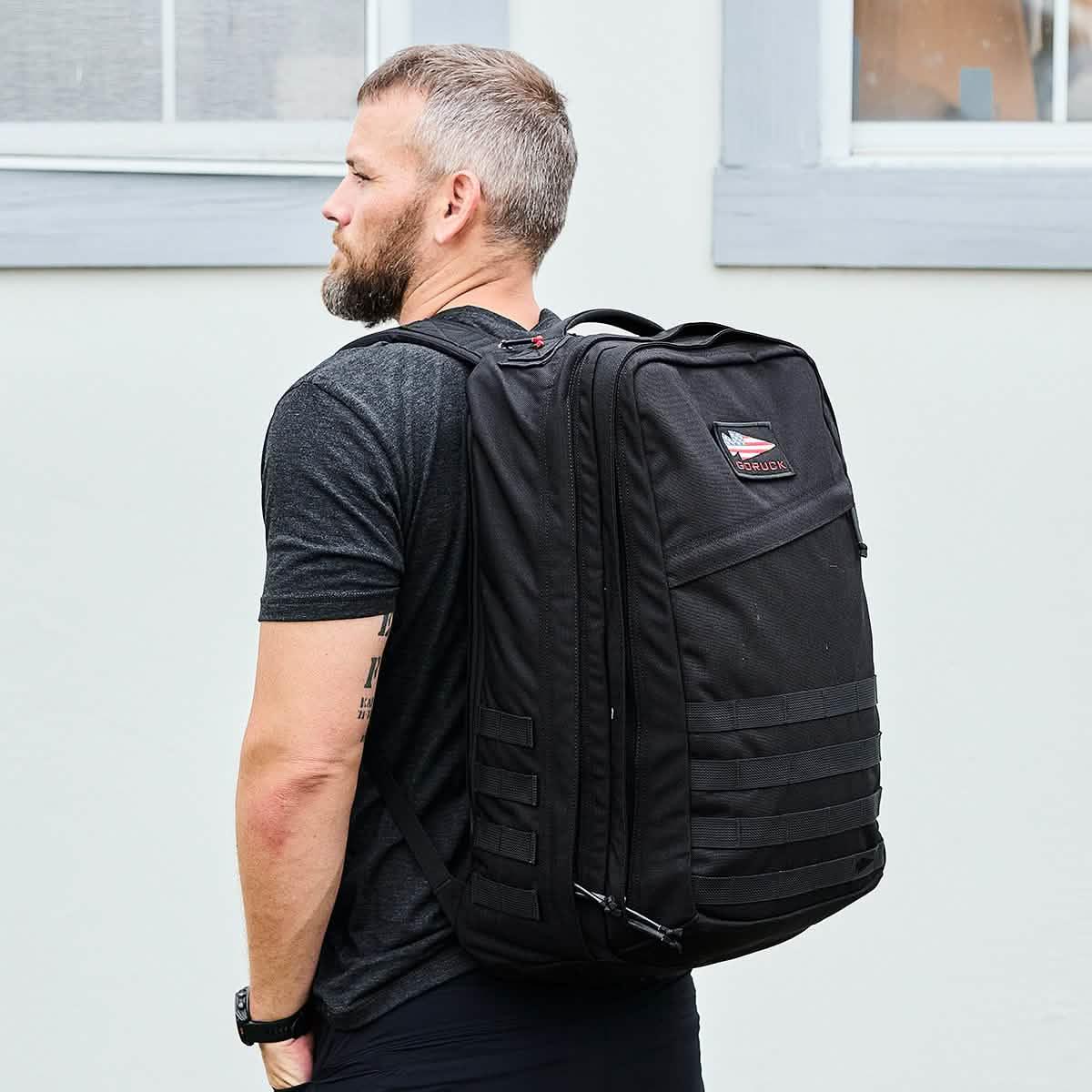 Man wearing a large black GORUCK rucksack outdoors, showcasing rugged rucking gear.