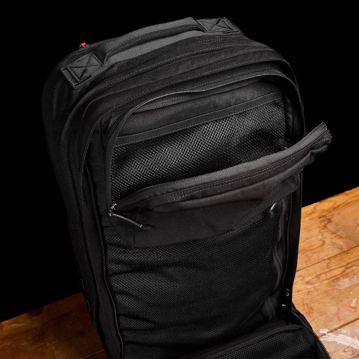 GORUCK Black 40L rucksack open, showing mesh interior pockets on wooden surface