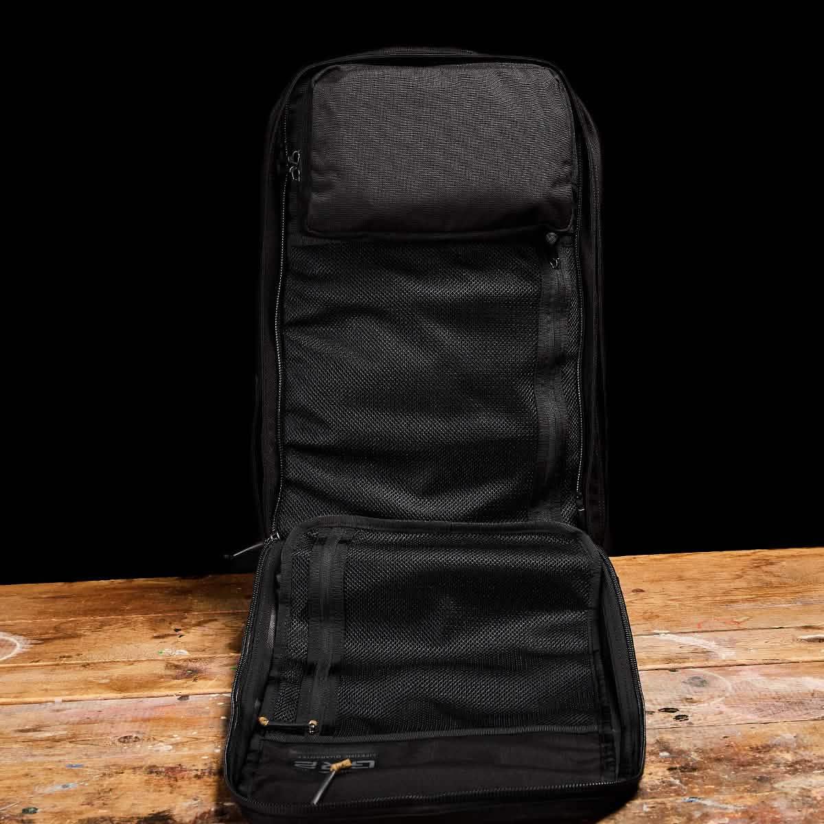 GORUCK black rucksack open flat on rustic wood table, showing mesh interior compartments