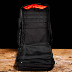 GORUCK black 40L rucksack open, showing interior mesh pockets and orange lining on wooden table