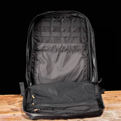The GR0 - Ripstop ROBIC® backpack stands upright on a wooden surface, showcasing its inner pockets and mesh compartment—ideal for a minimalist, water-resistant everyday carry setup.