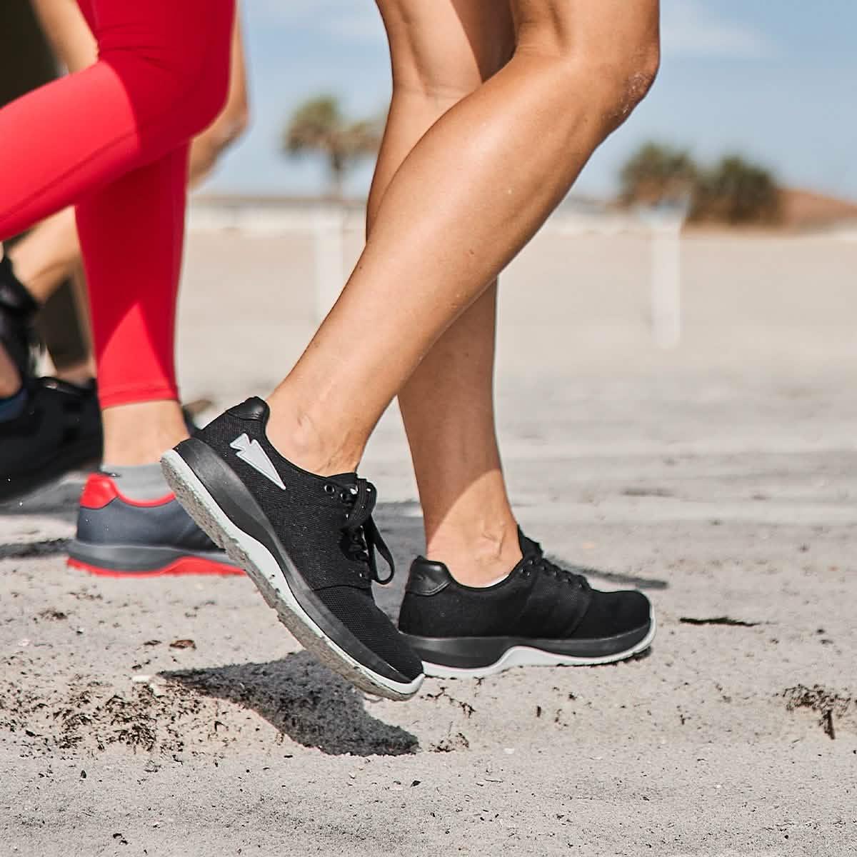 People rucking on sand wearing GORUCK black and grey athletic shoes outdoors