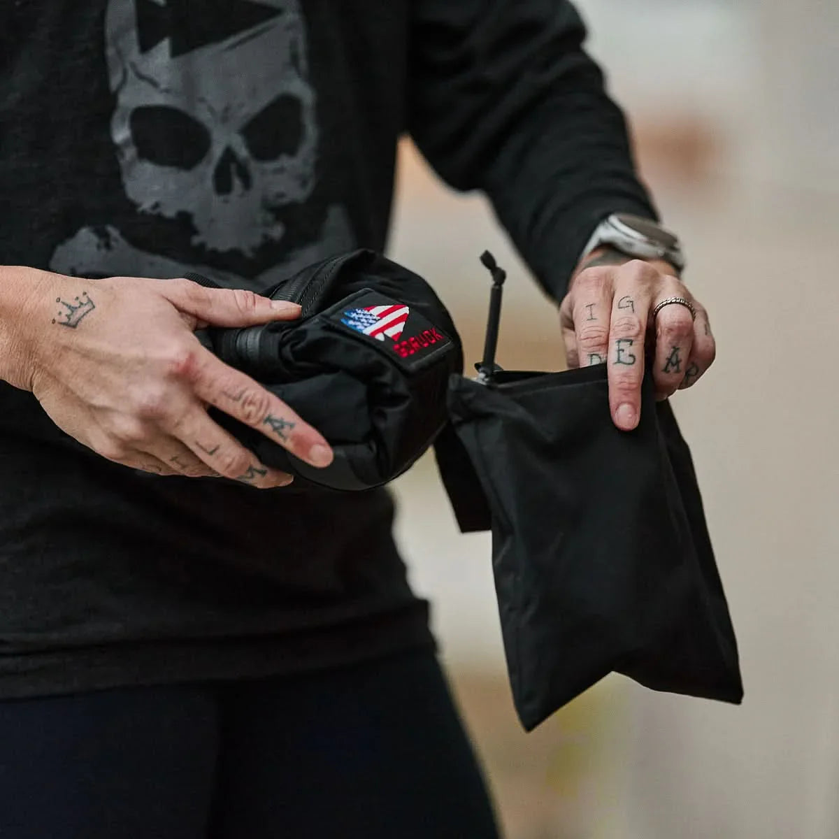 Person holding a compact black GORUCK packable bag with American flag patch