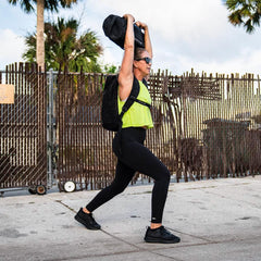Woman rucking with GORUCK backpack and sandbag outdoors, performing overhead lunge exercise