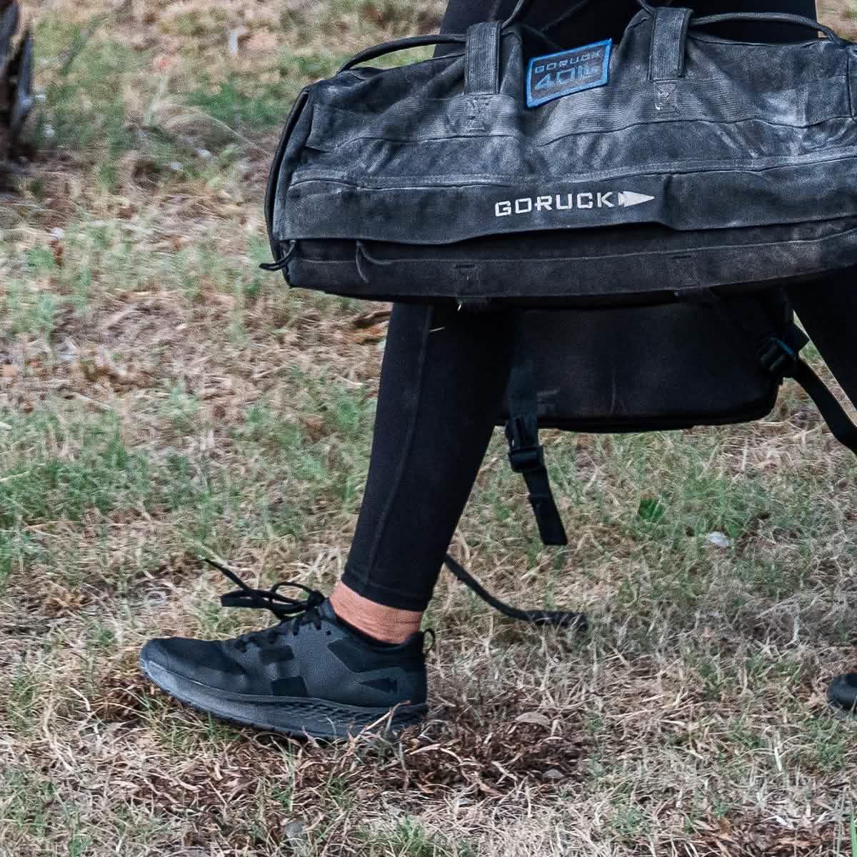 GORUCK sandbag and black rucking shoes on grass, outdoor fitness training gear