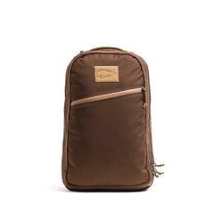 The Double Bullet Ruck w/ Bombproof Laptop Compartment - 18L is a brown travel backpack with double compartments, a diagonal front zipper pocket, tan upper patch, and an ultra-protective laptop sleeve.