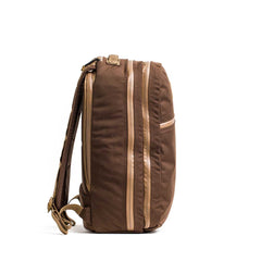 Side view of the brown Double Bullet Ruck w/ Bombproof Laptop Compartment - 18L, featuring tan zippers, padded shoulder straps, and a bombproof laptop compartment, shown against a white background.