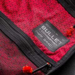 Close-up of a red and black Bullet Ruck x Carryology - GRXC2 Samurai 2.0 label, showing two compartments and zipper pulls on this limited-edition backpack inspired by the JPXDP 17oz Black Samurai Sashiko design.