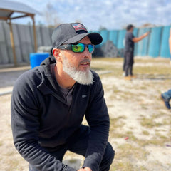 Man in black GORUCK Cadre hat and sunglasses outdoors at rucking training event