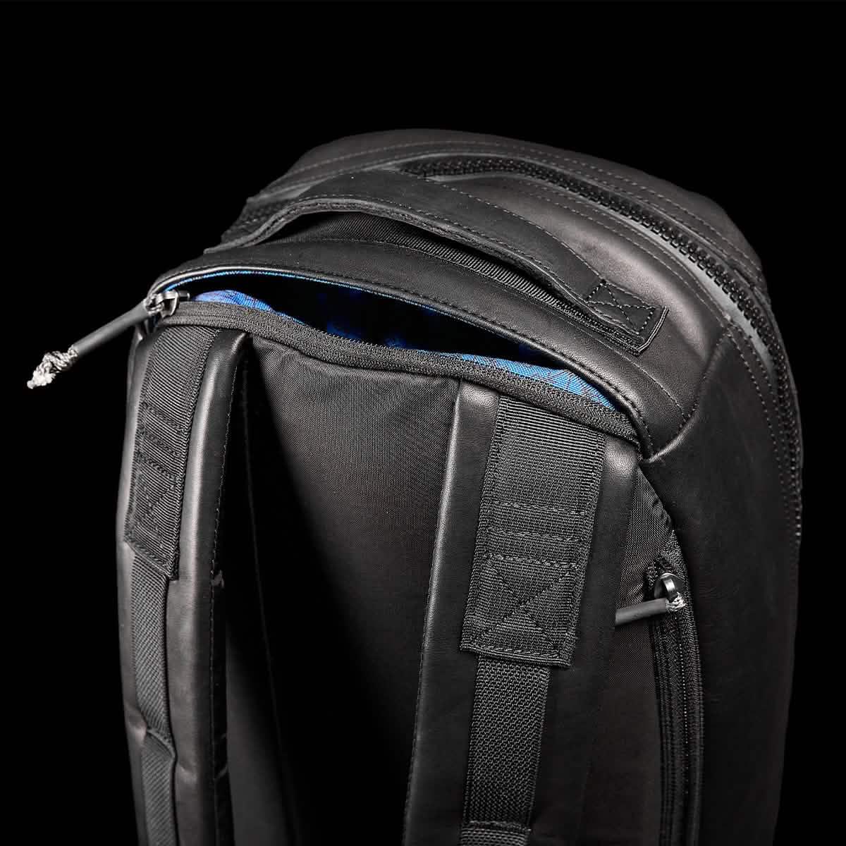 Close-up of GORUCK black rucksack shoulder straps and zippered compartment on black background