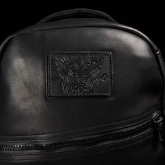 Close-up of GORUCK black leather rucksack with embossed patch and front zipper pocket
