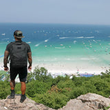 Man wearing GORUCK black Challenge Shorts and backpack overlooking a scenic beach