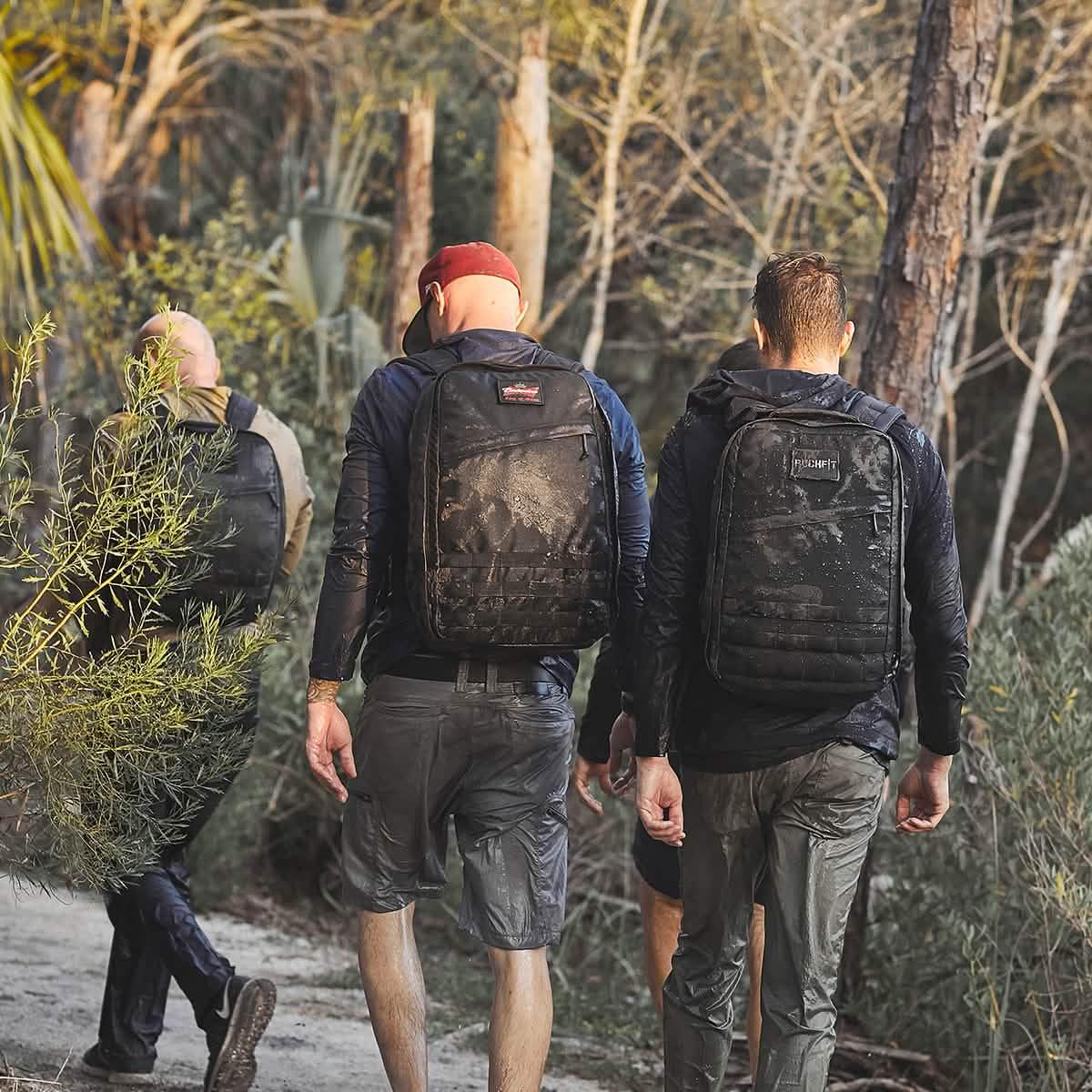 Three men rucking on a dirt trail wearing GORUCK packs and outdoor apparel in a wooded area