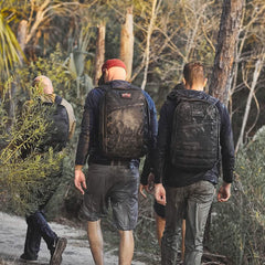 Three men rucking on a dirt trail wearing GORUCK packs and outdoor apparel in a wooded area