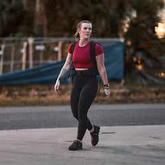 Woman rucking outdoors wearing GORUCK gear, red top, black leggings, rucksack
