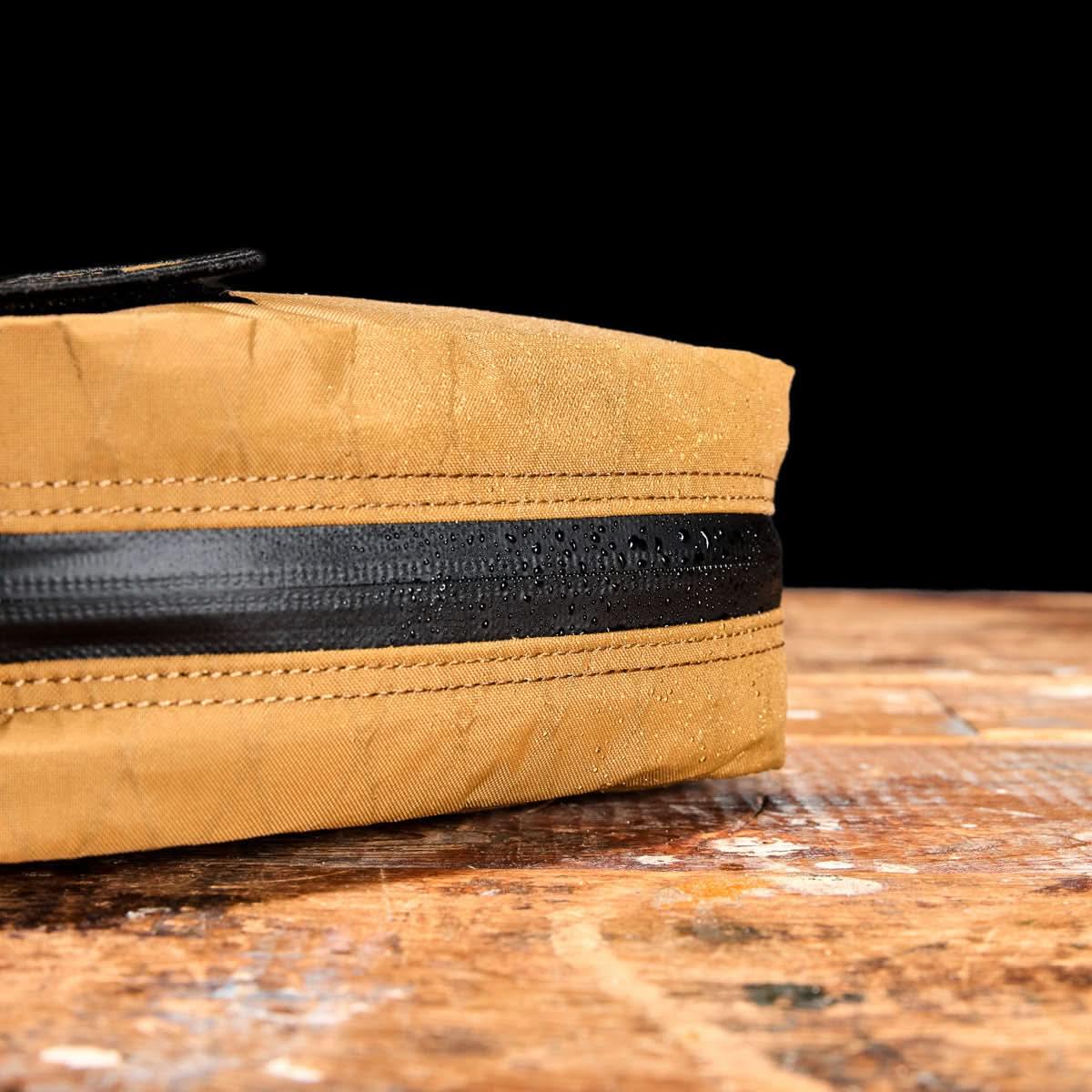 GORUCK coyote brown XPac bag detail with water-resistant zipper on wooden surface