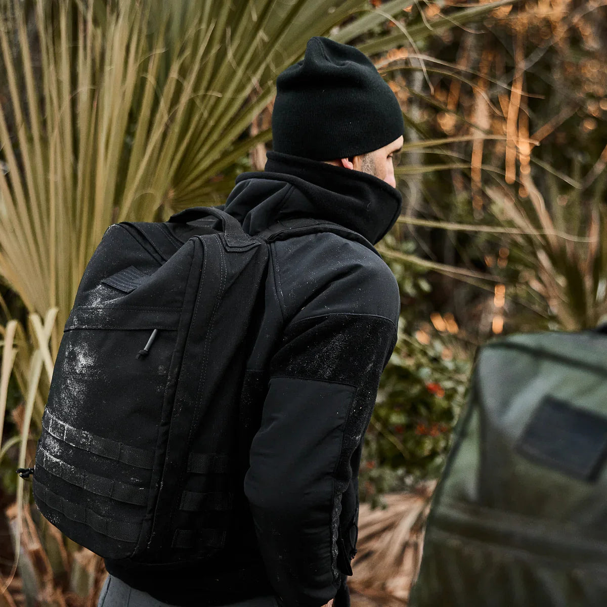Man rucking outdoors with GORUCK black backpack and beanie in rugged natural setting