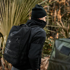 Man rucking outdoors with GORUCK black backpack and beanie in rugged natural setting