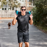 Man rucking with GORUCK training sandbag outdoors, wearing black shirt and sunglasses