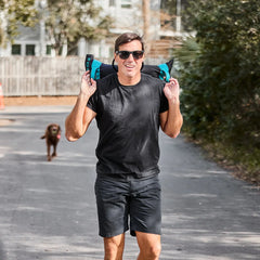 Man rucking with GORUCK training sandbag outdoors, wearing black shirt and sunglasses
