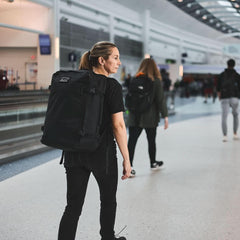 Woman wearing GORUCK backpack walking through airport terminal
