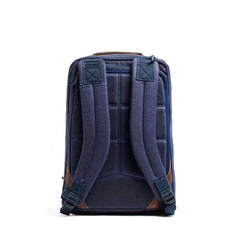 The GR1 USA - Heritage Waxed Canvas rucksack in navy blue features padded straps and brown accents, displayed from the back against a white background.