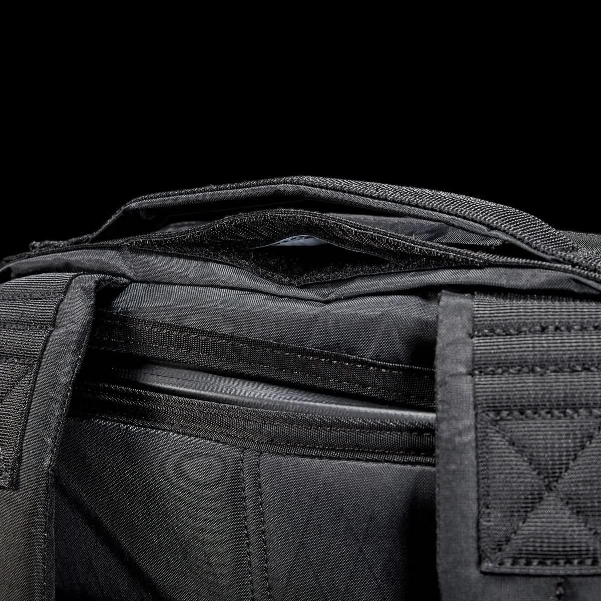 GORUCK black ruck backpack top handle and zipper detail against black background