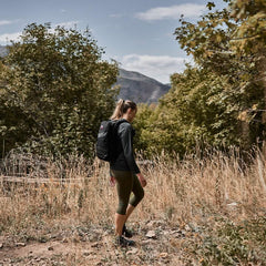 Woman rucking outdoors in GORUCK cropped leggings and black backpack in a scenic nature setting