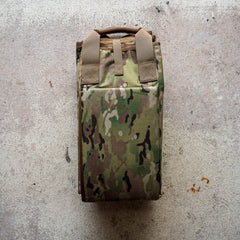 A folded camouflage-patterned Shooting Mat rests on a textured concrete surface.