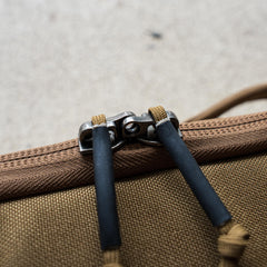 Close-up of a brown zipper with two black cord pulls on the textured fabric of a Rifle Case.
