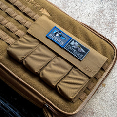 A brown Rifle Case with patches reading "GORUCK firearms gear" displayed on a textured surface.