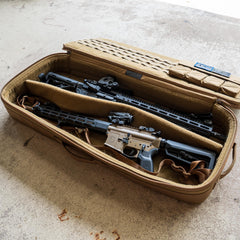 A tan Rifle Case with its lid open is displayed on a concrete floor, holding two rifles.