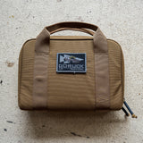 The brown Pistol Rug with handles and a "GORUCK Tactical" patch sits on a light textured surface—ideal as a modular pistol case or magazine pouch.
