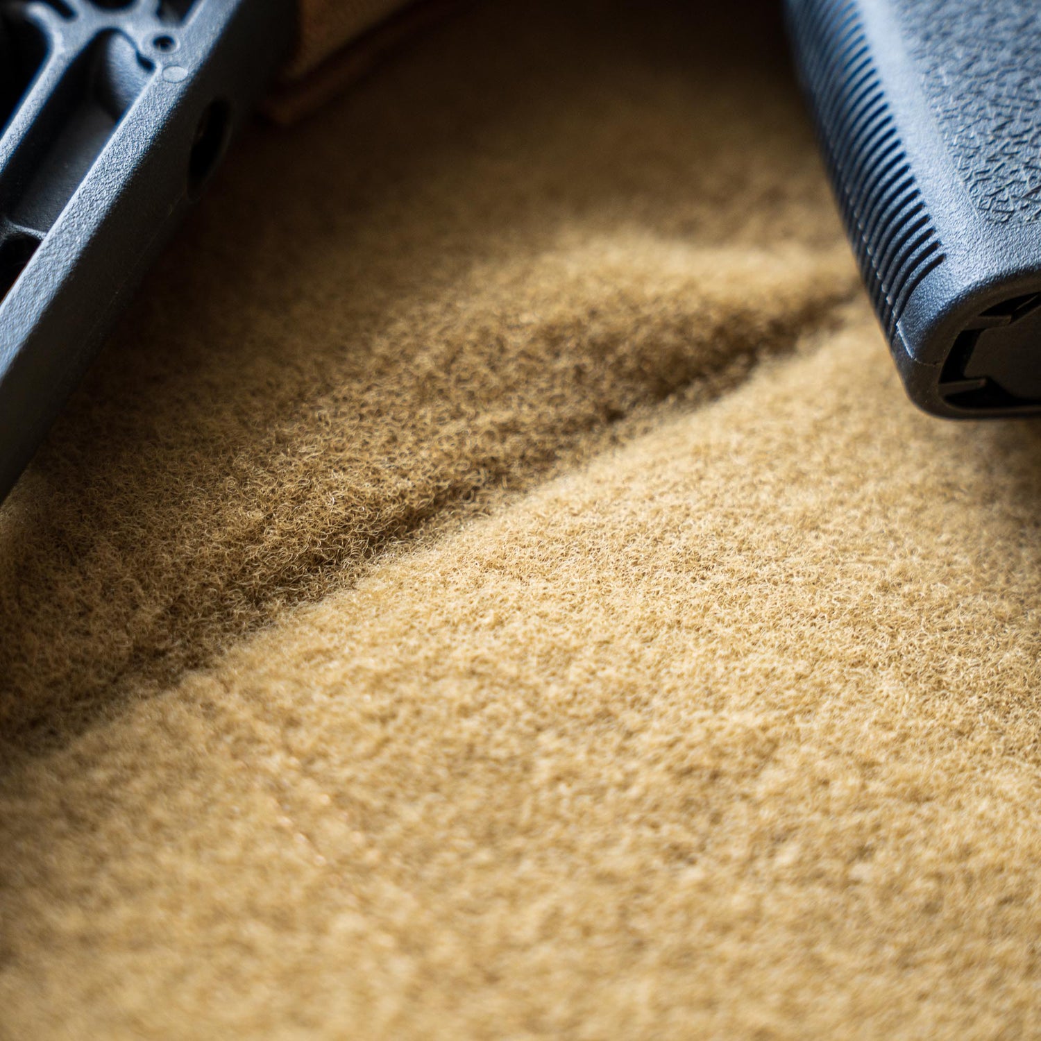 Close-up of a Rifle Case in black, resting on a soft, tan-colored fabric surface.