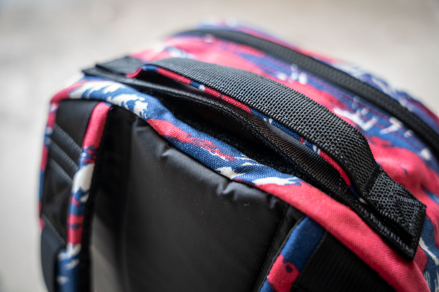 Close-up of the Bullet Ruck Classic - Ballistic Nylon Cordura’s streamlined handle with red, blue, and white patterned fabric—ideal for your 15L daypack or rucking backpack needs.